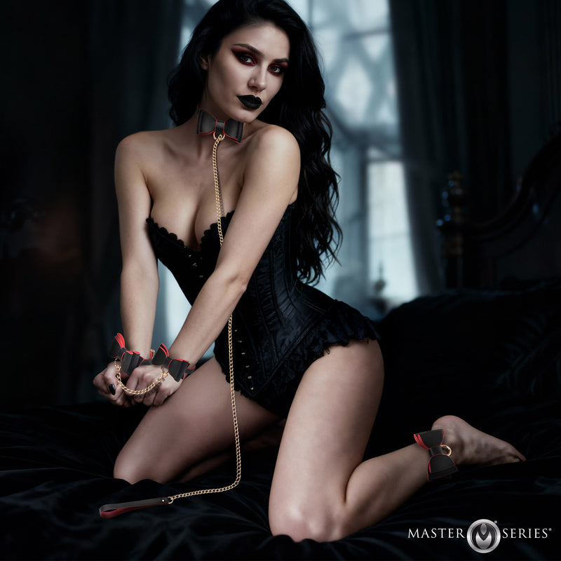 Master Series Goth BDSM set: black and red faux leather bow collar, gold chain leash, wrist and ankle cuffs, worn by a model