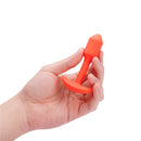 Orange Vibrating Snug Plug held between fingers to show its small size