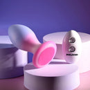 Paradise Plug tipped on its side to show the flat pink base, remote beside it