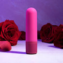 Selopa Tiny Temptation: pink silicone bullet vibrator with a rounded tip and berry-colored base, among red roses