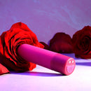 Pink Tiny Temptation lying on its side, showing the power button and charging contacts on the base