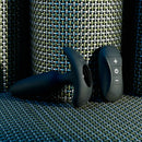 Black Beauty plug lying on its side, showing the charging port in the base, beside the remote