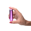 Purple metallic Bang! bullet held between thumb and fingers to show its small size